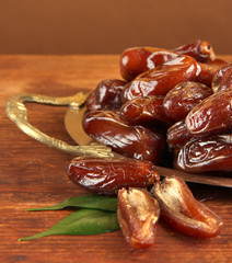 Dried dates on metal tray on wooden background