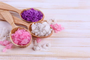 Wooden spoons with sea salt, on color wooden background