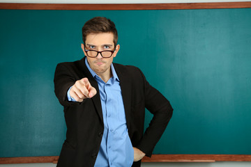 Young teacher near chalkboard in school classroom
