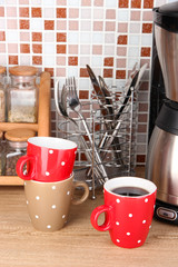 Cups and coffee maker in kitchen