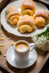 Breakfast in bed with espresso, flower and croissant