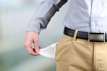 Man showing his empty pocket on bright background