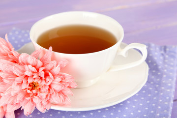 Pink chrysanthemums and cup of tea on wooden table