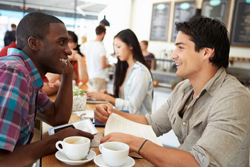 Two Male Friends Meeting In Busy Coffee Shop