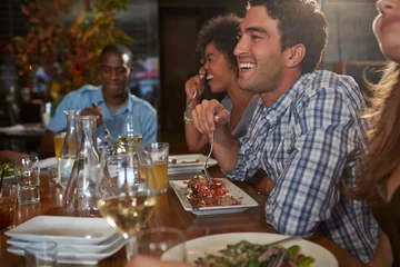 Foto op Plexiglas Restaurant Groep vrienden die van maaltijd in restaurant genieten
