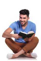 seated young casual man reading a book and smiles