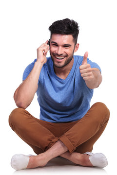 seated  man talking on  phone and making ok