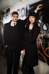 Young business couple at the grunge graffiti wall underground