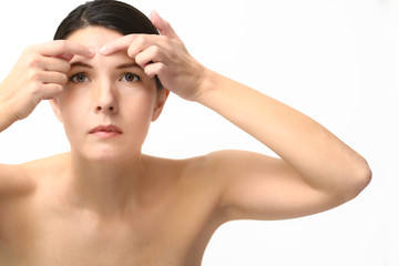 Naklejka premium Young woman squeezing a pimple on her forehead