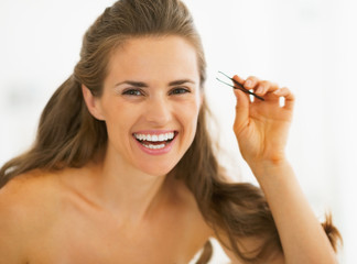 Happy young woman with tweezers