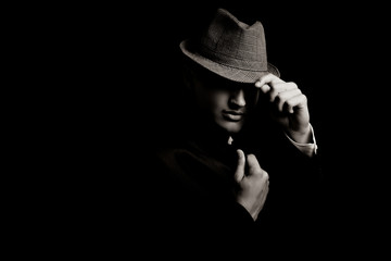 Fototapeta low key portrait of young gangster with hat in the darkness. obraz