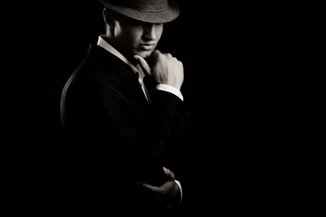low key portrait of young gangster with hat in the darkness.