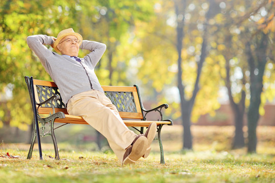 Senior gentleman sitting on a bench and relaxing in a park