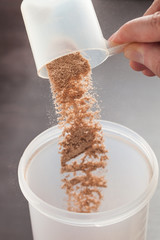 Scoop of chocolate whey isolate protein in front of shaker