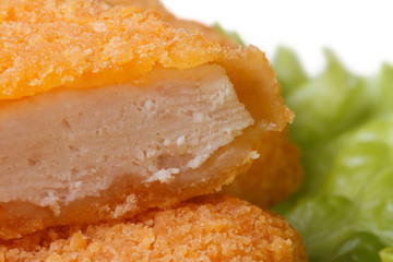 Fresh chicken nuggets cut into green lettuce close up. macro