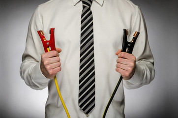 Man wearing tie holding jumper cables
