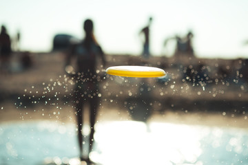 frisbee in a spray of water against the beach - obrazy, fototapety, plakaty