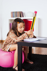Little girl writing with a giant pencil