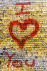 i love you heart graffiti on a yellow brick wall