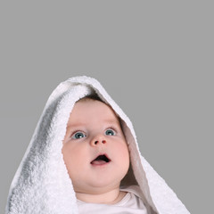 baby in white towel stares up smiling