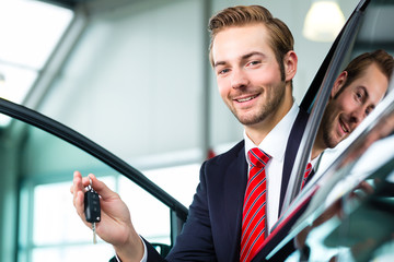 Verkäufer mit Auto im Autohaus