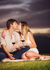 Couple drinking glass of wine on romantic sunset picnic