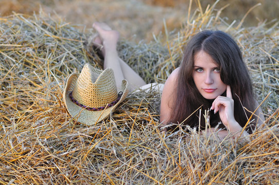 Nude girl lies on senovalle near cowboy hat