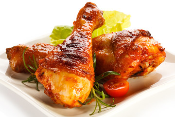 Grilled chicken legs and vegetables on white background