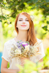 Naklejka premium Redhead girl with flowers at outdoor.