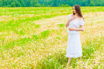 Fototapeta premium girl in a white sundress walking on chamomile field