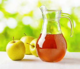 Jug of apple juice on nature background
