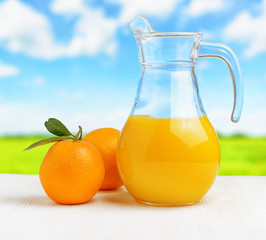 Jug of orange juice on nature background