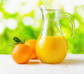 Jug of orange juice on nature background