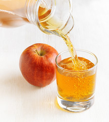 Apple juice pouring from jug into a glass