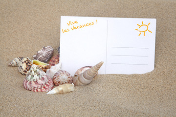 carte postale et coquillage sur le sable