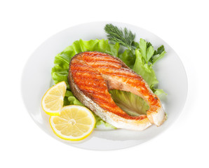 Grilled salmon with lemon slices and herbs on plate