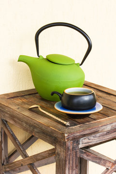 Green tea in cup and teapot on wooden table