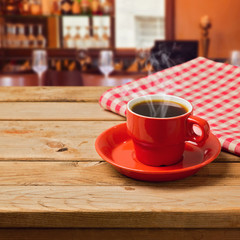 Coffee cup with checked tablecloth on wooden table