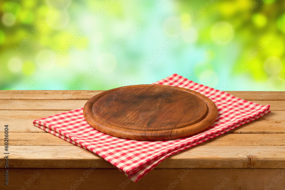 Wall mural round board on tablecloth on wooden table over bokeh background