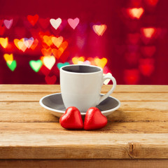 Coffee cup with heart shape chocolate over bokeh