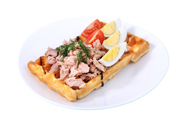 Belgian waffle with ham, boiled egg and tomato on white.