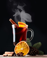 Mulled wine, blue pine tree branch and spices on wooden