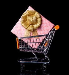 Shopping cart with gift box isolated in black