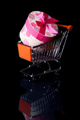 Shopping cart with gift box isolated in black
