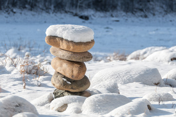Stones in balance on the winter coast under snow