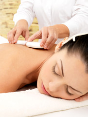 Obraz na płótnie Canvas Woman having hot stone massage of body in spa salon