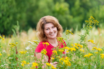 Naklejka na ściany i meble Middle-aged woman on a meadow with tansy