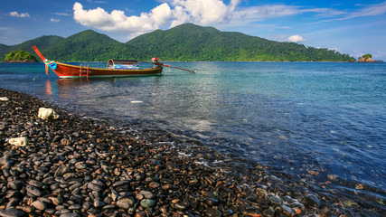 Long tail boat floating on beautiful pebble beach