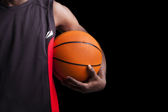 Image of a basketball player holding a ball against dark backgro