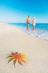 Lovers couple at sandy sea beach with red starfish